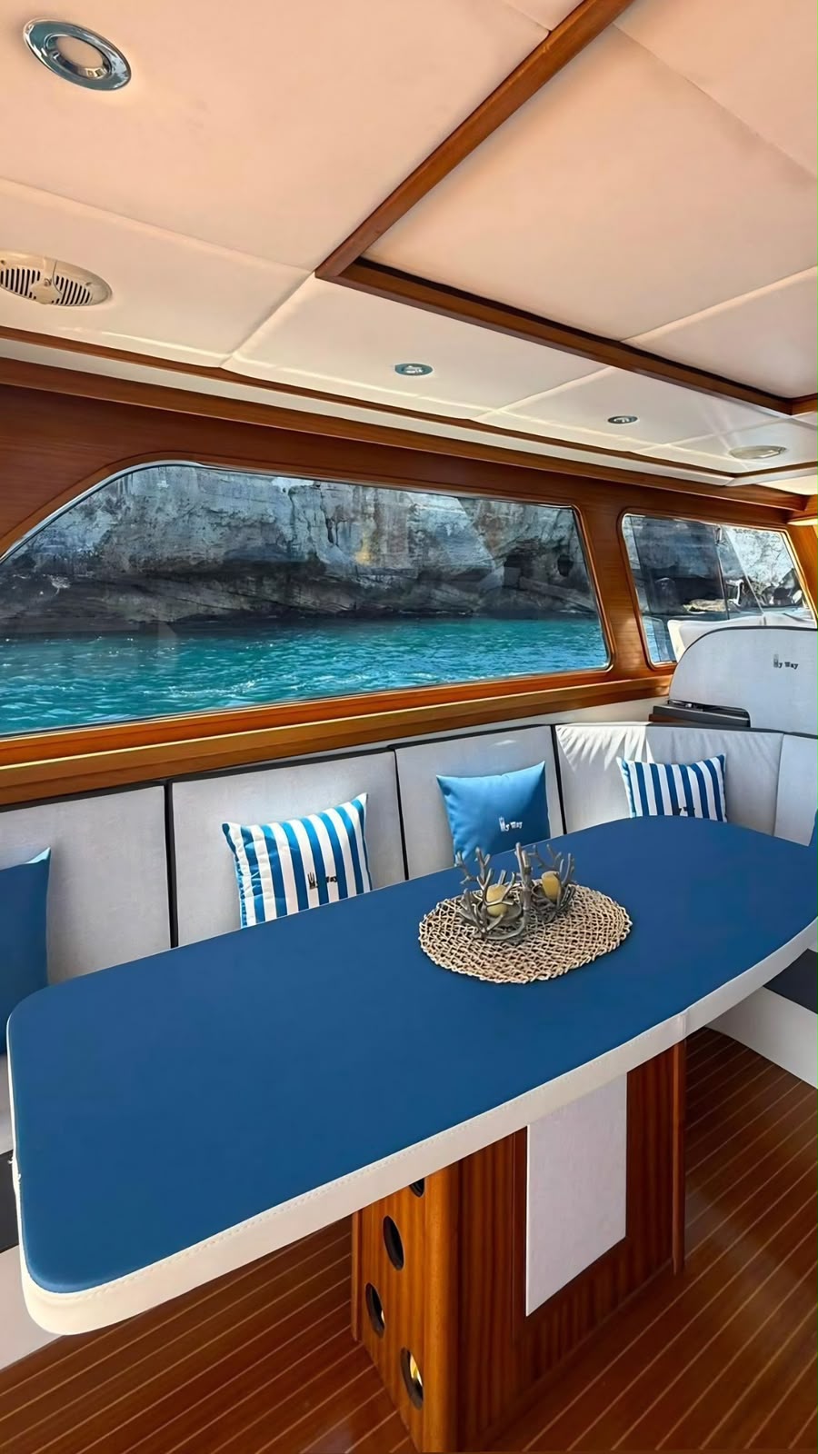 Yacht charter Savelletri, tavolo interno in mogano con vista grotte